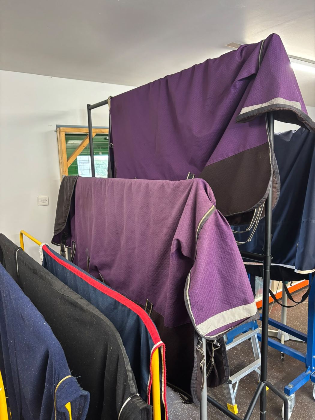 Purple and navy horse rugs drying on racks